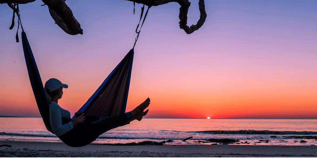 Woman in hammock with sunset, sunset over ocean, woman in hammock watching sunset